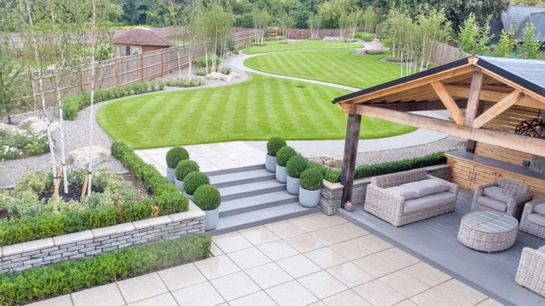 Aerial view of a modern backyard with patio, wooden pergola, landscaped lawn with diagonal stripes, and seating areas