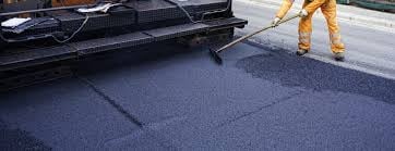 Worker operating asphalt paving machine