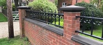 Black metal gate fence on red brick pillars