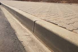 Concrete curb and paved sidewalk meeting asphalt road at street level perspective